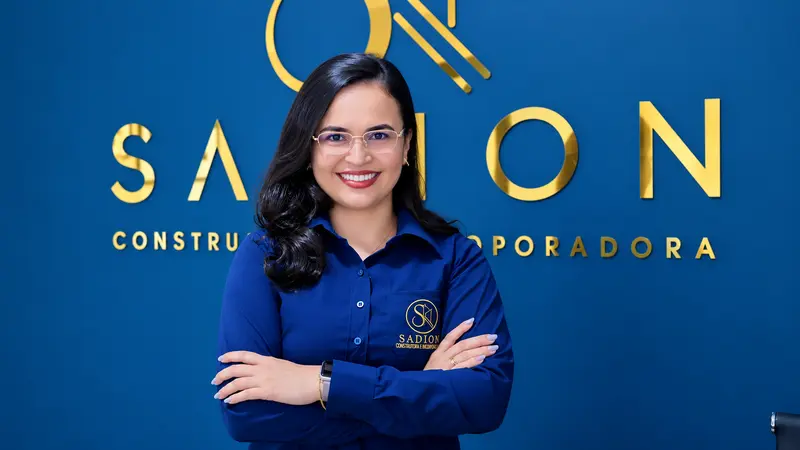 Consultora da Sadion sorrindo em frente ao logotipo da empresa