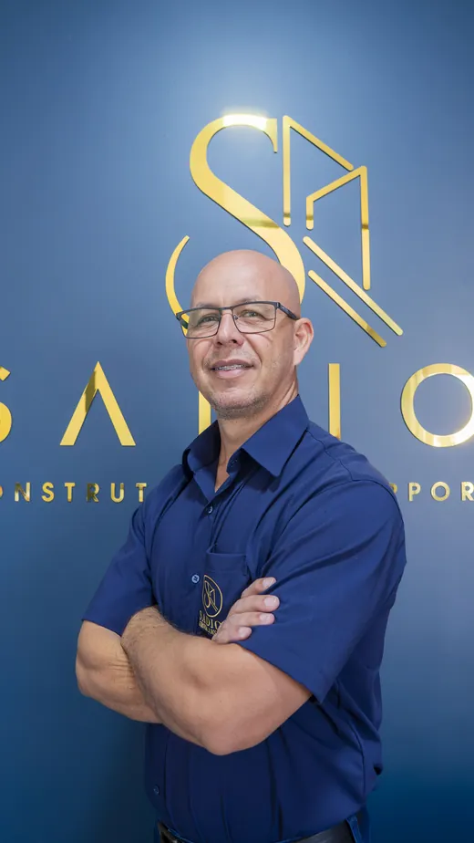 Responsável pelo operacional da Sadion em frente ao logotipo da empresa